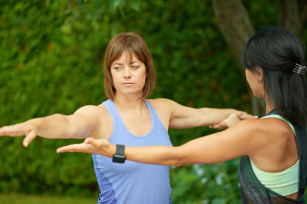 Two mature women keeping fit by doing yoga in the summer